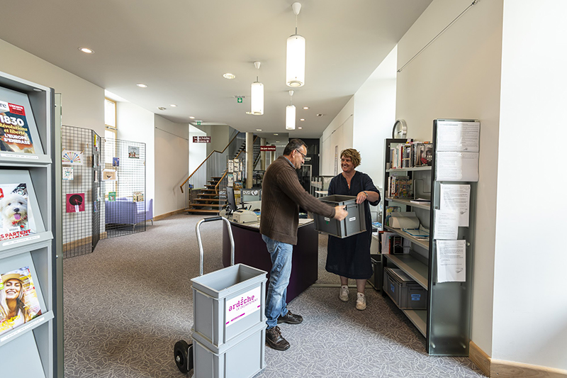 Bibliothécaire départemental donnant une caisse de livre à une bibliothécaire municipale