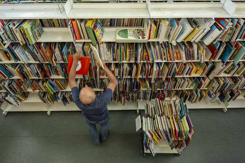 Bibliothécaire rangeant des livres sur une étagère.