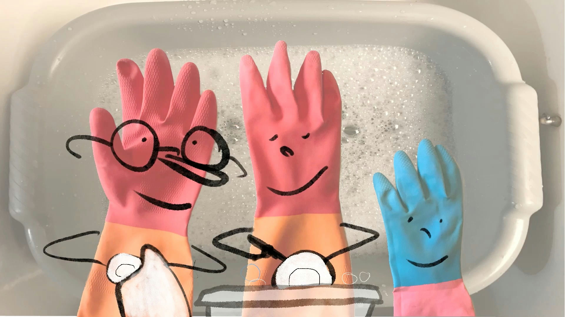 Photo de gants en latex rose au dessus d'une bassine de mousse sur lesquel sont dessinés des visages
