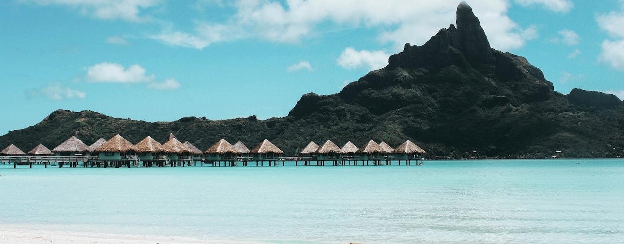 photo d'une plage bleue avec des parasols blanc et la montagne en arrière plan