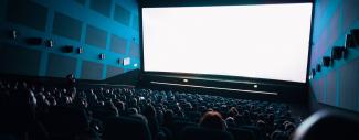 salle de cinema dans le noir avec public regardant un écran blanc