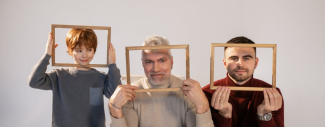 photo d'un jeune garçon, un adulte et un senior tenant des cadres en bois devant leur visage