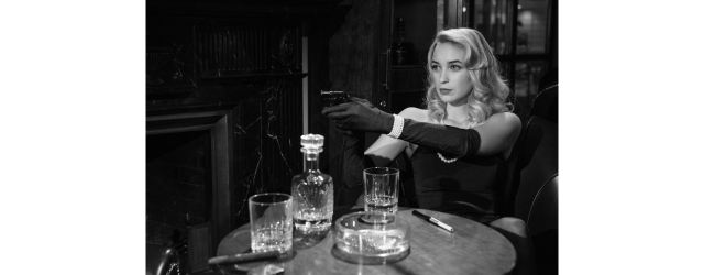 photo de femme en noir et blanc assise et visant avec un pistolet extrait d'un film