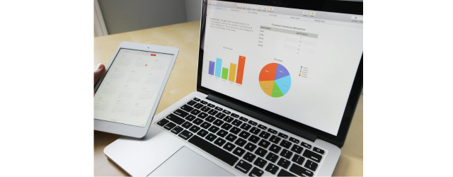 ordinateur portable ouvert avec des graphiques et tablette posés sur une table