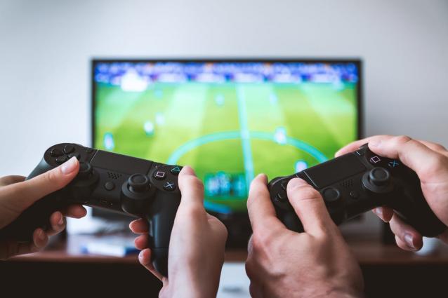 deux mains tenant des manettes devant une télévision